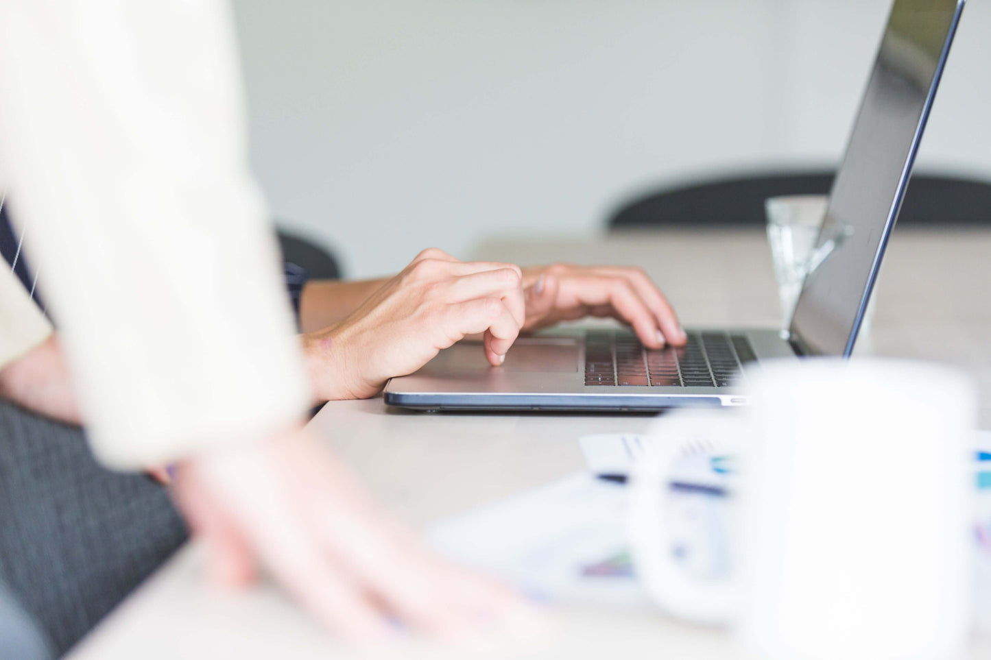 Hands typing on a laptop keyboard during an HR system setup meeting.